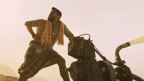 a man with a towel around his neck stands next to a motorcycle