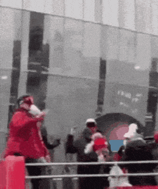 a group of people are standing in front of a building wearing santa hats and gloves .