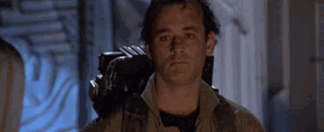 a close up of a man 's face in a room with a camera on his back .