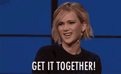 a woman is smiling and saying `` get it together '' while sitting in front of a blue background .
