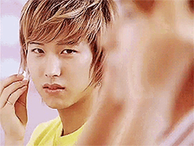 a young man wearing a yellow shirt is looking at the camera