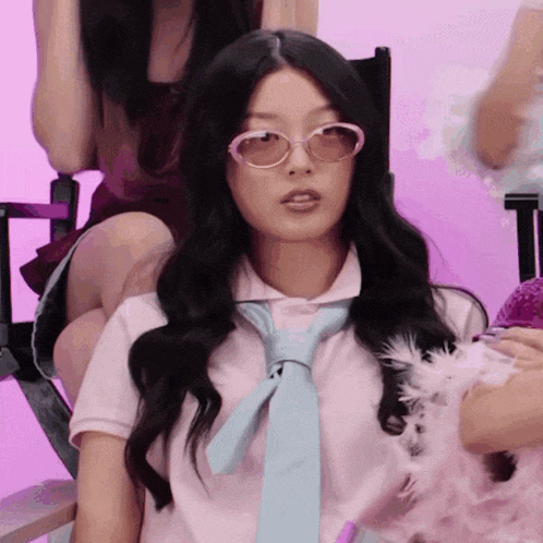 a woman wearing sunglasses and a tie is sitting in a director 's chair