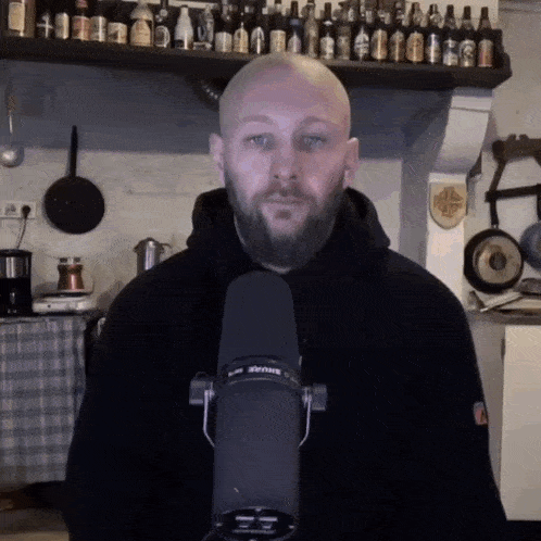 a man with a beard is holding a shure microphone
