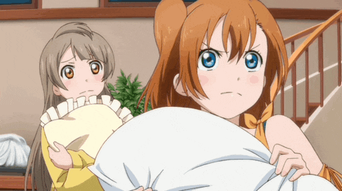 a girl with orange hair is holding a pillow next to another girl with brown hair