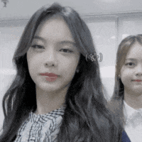 two girls are standing next to each other and one of them has a piercing in her ear .