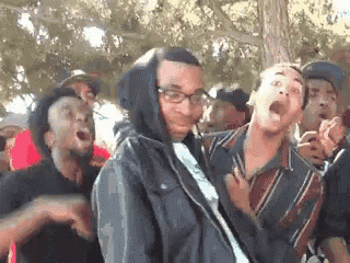 a group of young men are standing in a park with their mouths open .