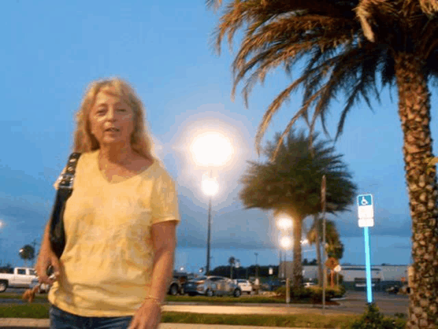 a woman in a yellow shirt stands in front of a handicap sign