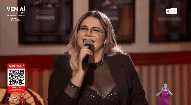 a woman singing into a microphone in front of a sign that says vem a live