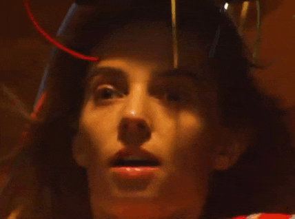 a close up of a woman 's face with a red light coming out of her head .