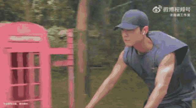 a man wearing a baseball cap and a purple tank top is riding a bike .