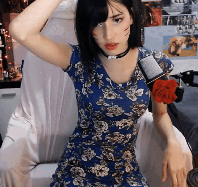 a woman in a blue floral dress is sitting in a chair