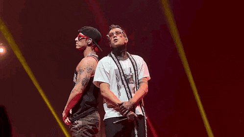 a couple of men are dancing on a stage in front of a crowd .