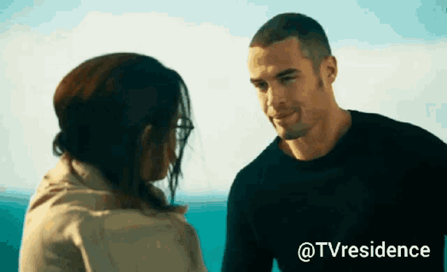 a man and a woman are looking at each other in front of the ocean with the words @tvresidence above them