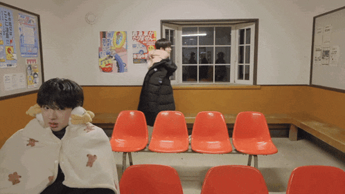 a woman holding a child in a waiting room with posters on the wall including one that says " pop "