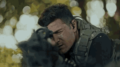 a man in a military uniform is looking through a gun scope