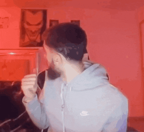 a man with a beard is drinking from a glass while wearing a nike hoodie .
