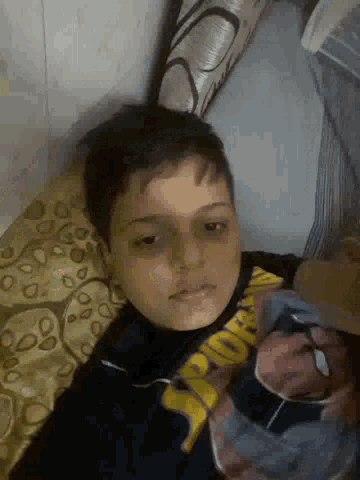 a young boy is laying on a bed wearing a spider man shirt .