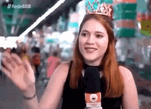 a woman with a crown on her head is talking into a microphone