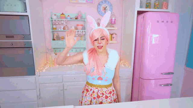 a woman in a pink bunny costume stands in front of a smeg refrigerator