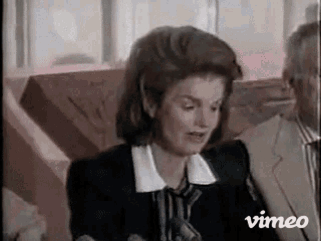 a woman in a suit is sitting next to a man in a suit .
