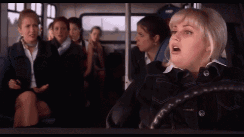 a woman sitting on a bus with her mouth open and a button on her jacket that says ' a ' on it
