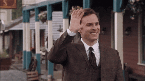 a man in a suit and tie is waving