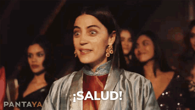 a woman says salud in front of a crowd
