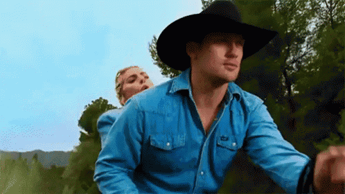 a man in a cowboy hat is riding a woman on his back .