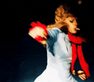 a woman in a blue shirt and red scarf is dancing