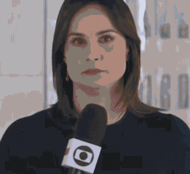 a woman is holding a microphone in her hand and looking at the camera .