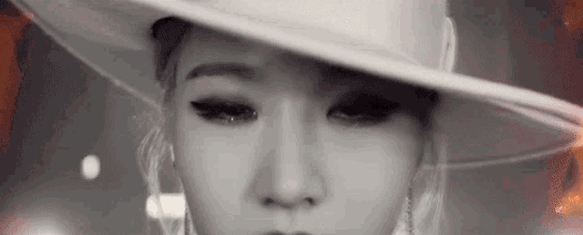 a black and white photo of a woman wearing a white hat .