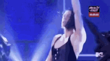 a woman in a black tank top is dancing on a stage in front of a mtv sign .