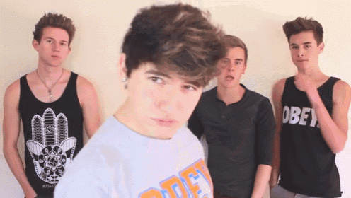 a group of young men are standing together and one of them is wearing a shirt that says obey