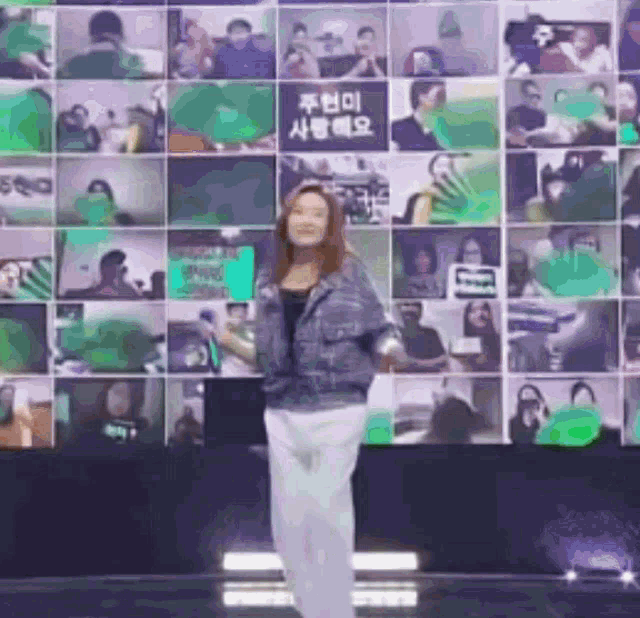 a woman is dancing in front of a wall with a lot of pictures on it .