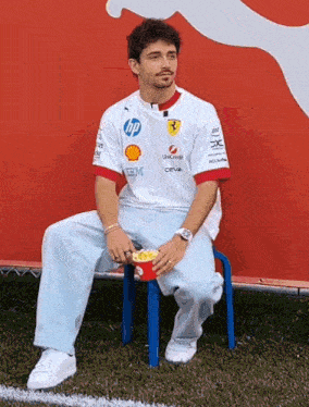 a man sitting on a blue chair with a box of popcorn in his hand