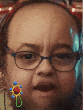 a man wearing glasses has a baby rattle on his face