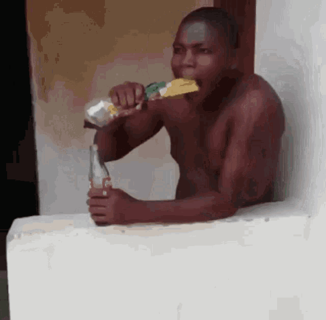 a shirtless man drinking a coca cola bottle