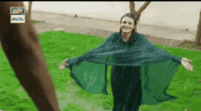 a woman is standing in the rain with her arms outstretched .