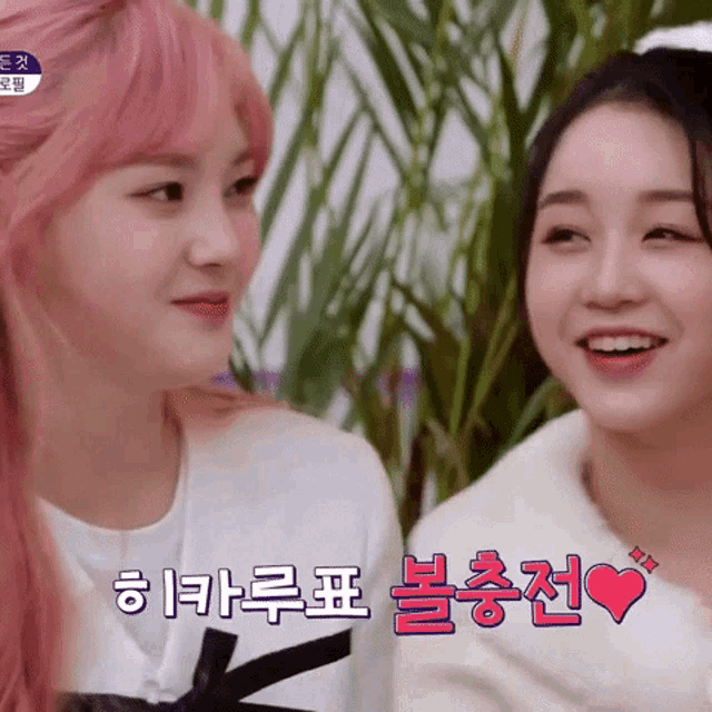 two girls with pink hair are looking at each other and one of them has a heart on her chest