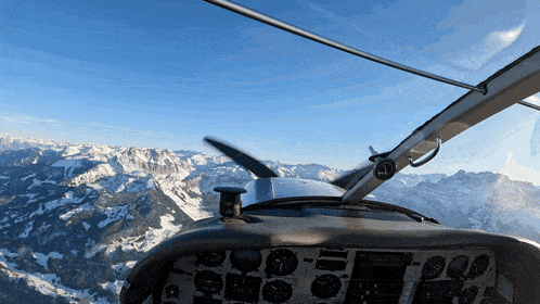 a plane is flying over a snowy mountain range with a propeller visible