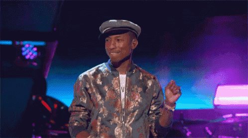 a man wearing a hat and a floral jacket is standing on a stage .