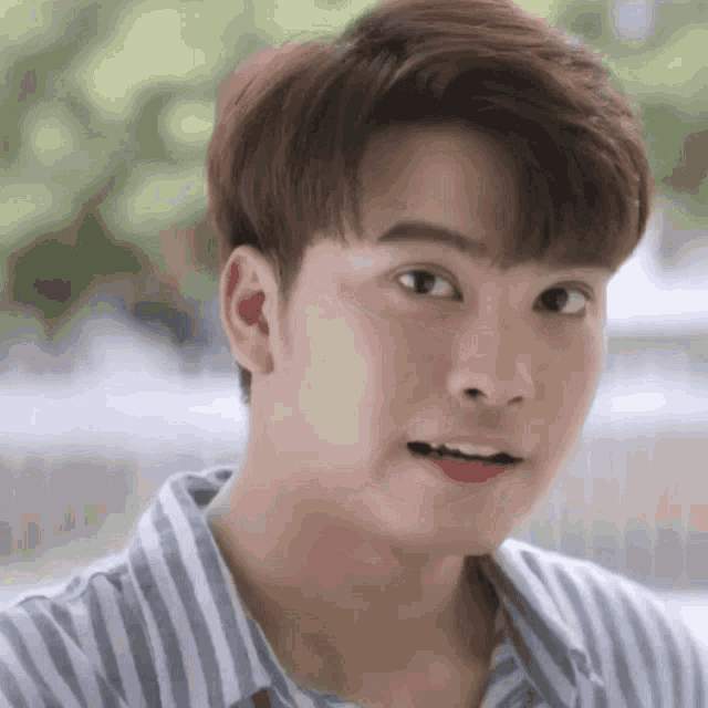 a close up of a young man 's face wearing a striped shirt .