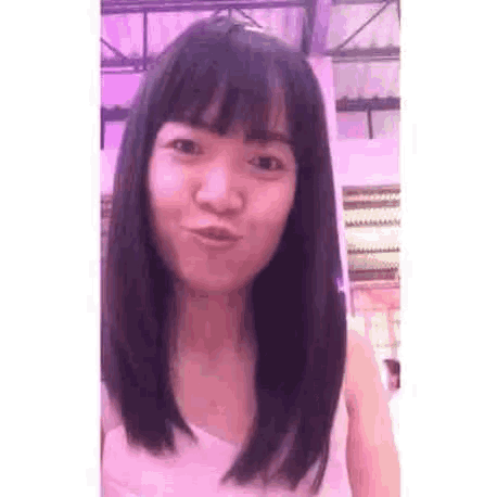 a woman with long black hair and bangs is making a face .