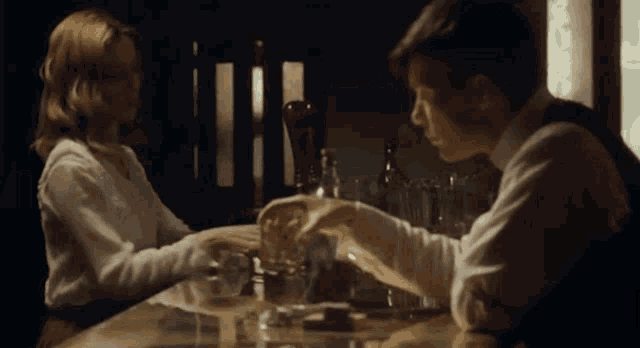 a man and a woman are sitting at a bar and holding hands