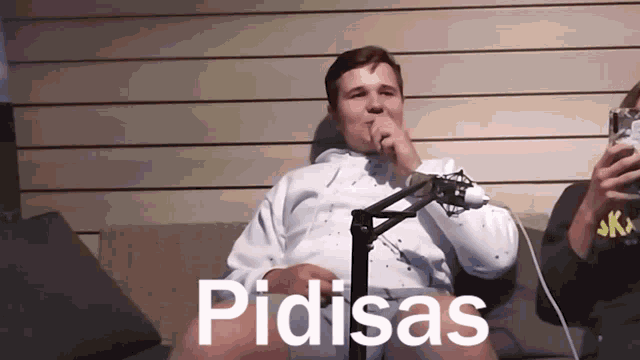 a man sitting in front of a microphone with pidisas written on the bottom right