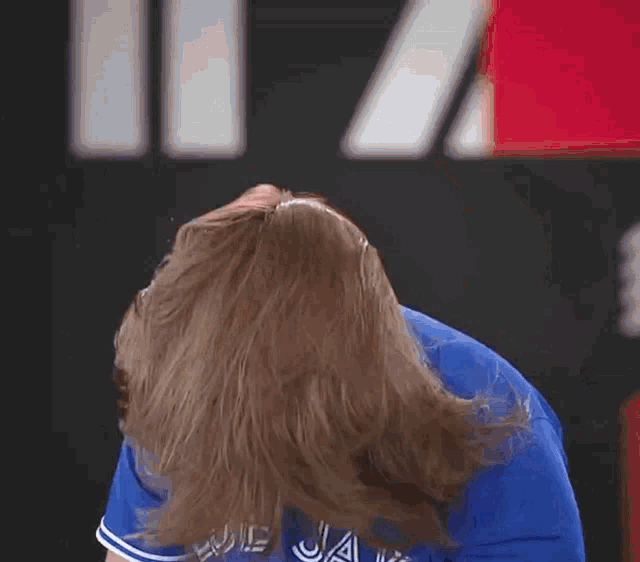 a man with long hair wears a blue jays shirt