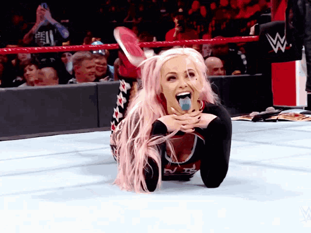 a woman with pink hair is laying on the ground with her tongue hanging out