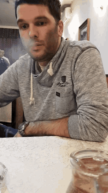a man wearing a grey sweater with a pocket that says ' abercrombie & fitch '