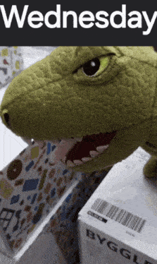 a stuffed crocodile is sitting next to a box that says byggla