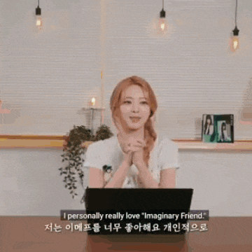 a woman is sitting at a table with a laptop computer and talking to someone .